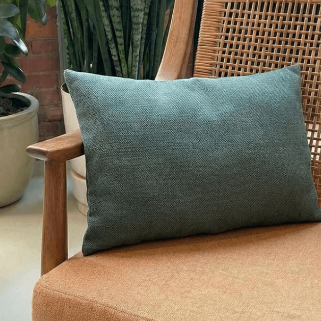 Broste Copenhagen cushion 40x60cm in green on brown wooden chair with potted plants behind