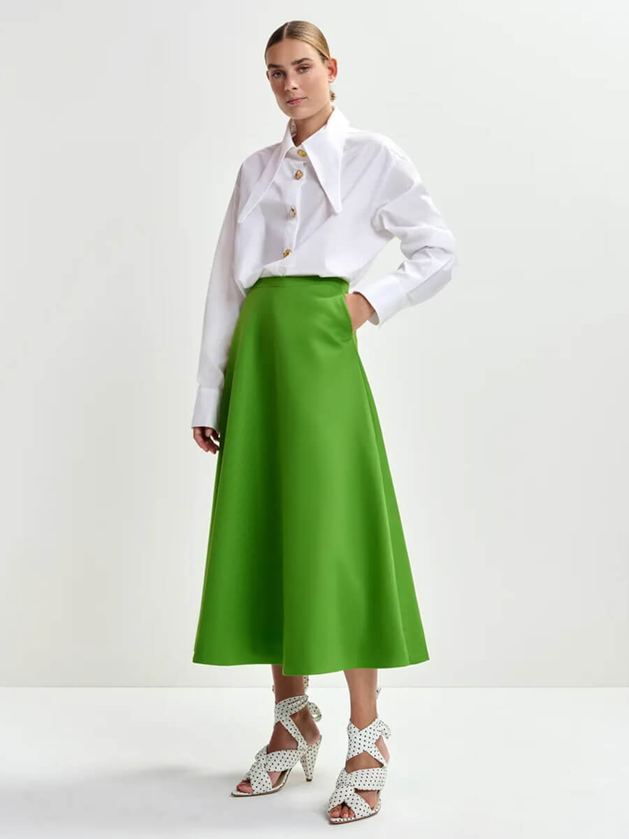 Model with slicked back hair wearing Essentiel Antwerp Julio Skirt – Green with white shirt tucked in and white heels with black polka dots