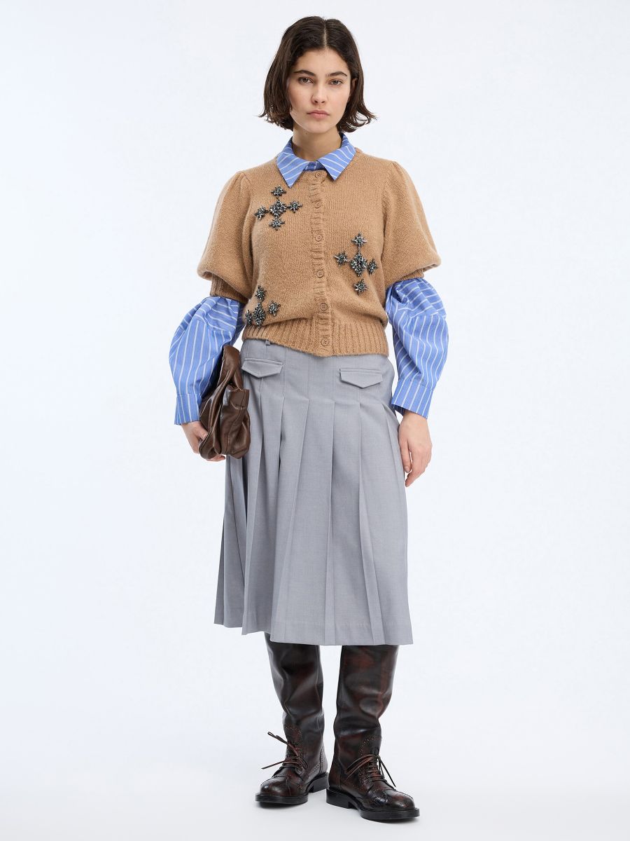 Munthe - Vocca Cardigan styled over a blue/white striped shirt with a grey pleated skirt and brown leather clutch bag and boots