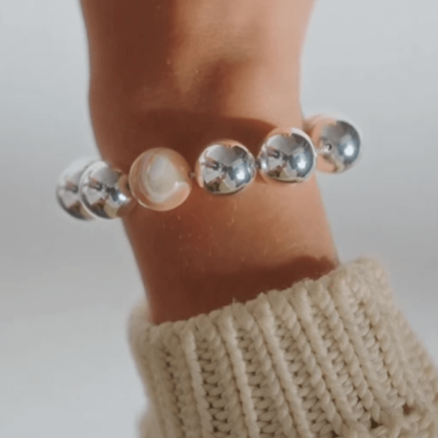 Anni Lu Hi Ho Silver Bracelet on models wrist with a cream knit cuff