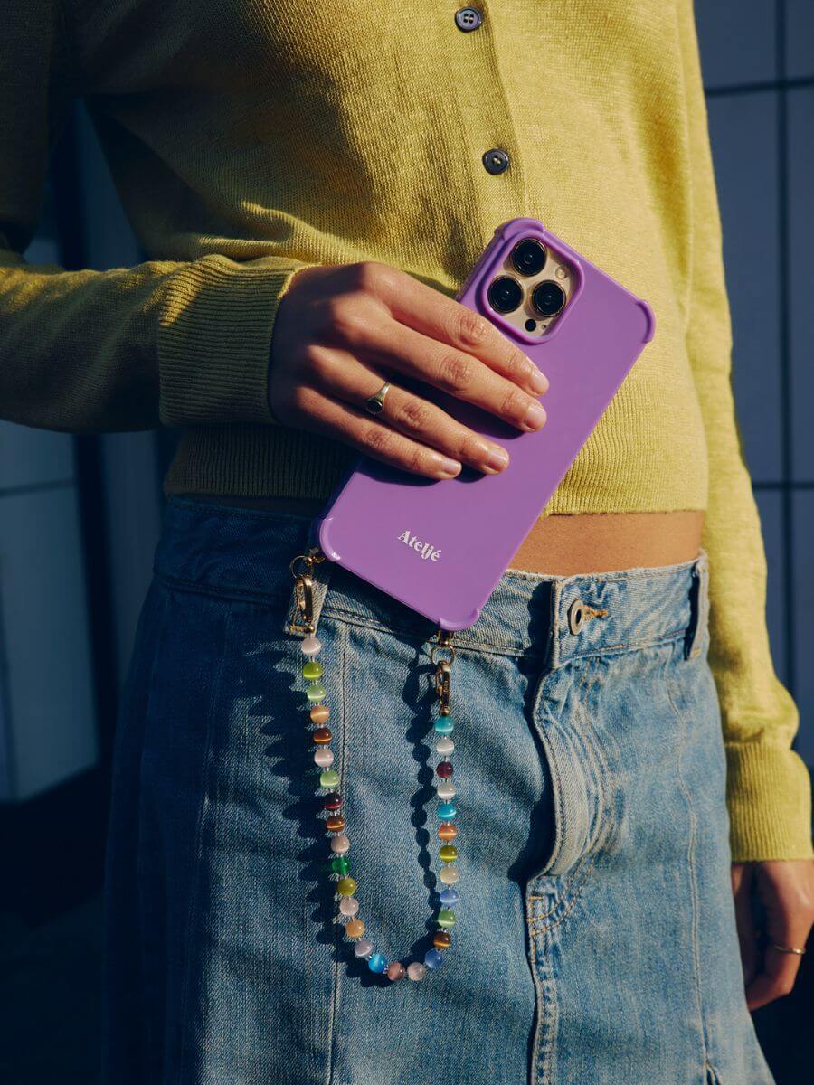 Atelje iphone case violet with Multi short cord held by model with yellow cardigan and denim skirt